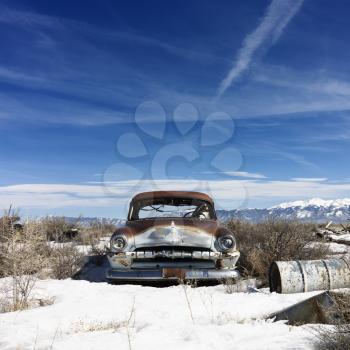 A deserted classic automobile in the remote countryside with snow on the ground. Horizontal shot.