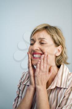 Smiling Caucasian woman holding hands up to cheeks.
