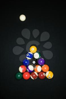Pool tables arranged in triangle on pool table with cue ball.