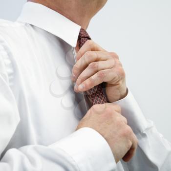 Caucasian middle aged businessman fixing necktie.