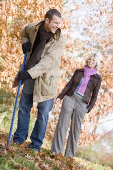 Royalty Free Photo of a Man Raking Leaves With a Woman Behind Him