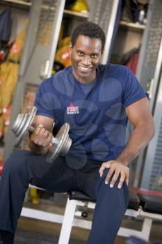 Royalty Free Photo of a Firefighter Doing Bicep Curls in the Locker Room