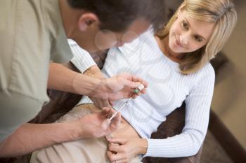 Royalty Free Photo of a Man Helping a Woman Put a Needle in Her Stomach