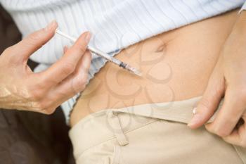 Royalty Free Photo of a Woman Putting a Needle in Her Stomach