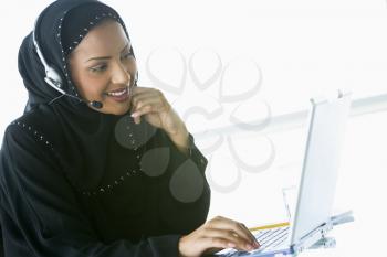 Royalty Free Photo of an Eastern Woman Wearing a Headset at a Laptop