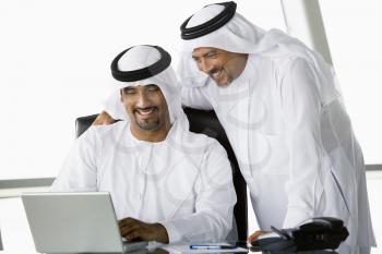 Royalty Free Photo of Two Eastern Men in an Office Looking at a Laptop