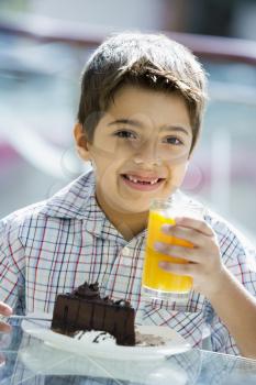 Royalty Free Photo of a Boy Eating Dessert and Drinking Juice