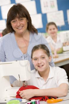 Royalty Free Photo of a Girl Sewing and a Teacher Behind Her
