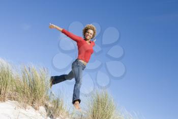 Royalty Free Photo of a Woman Jumping Over Sand Dunes