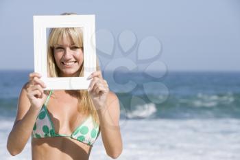 Royalty Free Photo of a Girl on the Beach Holding a Frame at Her Face