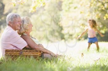Royalty Free Photo of Grandparents at a Picnic Watching Their Young Granddaughter