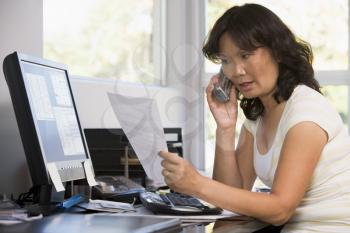 Royalty Free Photo of a Woman Looking at Papers Talking on the Telephone