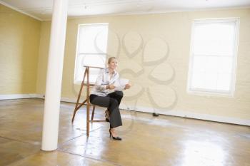 Royalty Free Photo of a Woman in an Empty Space Sitting on a Ladder