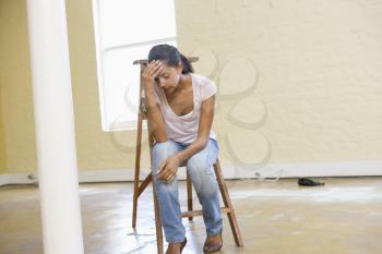Royalty Free Photo of a Woman Sitting on a Ladder in an Empty Room