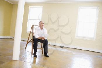 Royalty Free Photo of a Man Sitting on a Ladder in an Empty Room