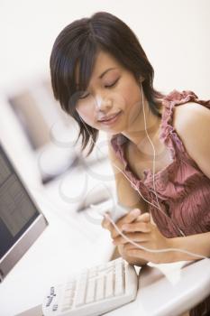 Royalty Free Photo of a Woman With an MP3 Player at a Computer