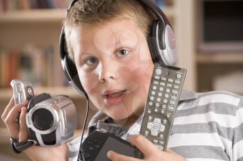 Royalty Free Photo of a Boy Wearing Headphones and Holding Many Technology Gadgets