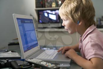 Royalty Free Photo of a Little Boy Using a Laptop and Listening to Music