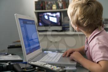 Royalty Free Photo of a Young Boy in the Bedroom With a Laptop