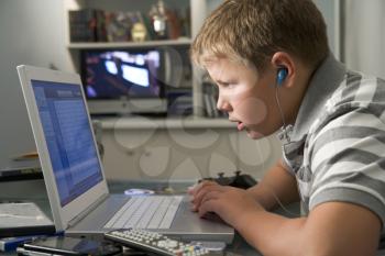 Royalty Free Photo of a Boy Listening to an MP3 Player While on a Laptop