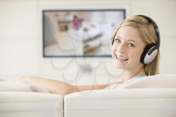Royalty Free Photo of a Woman in a Living Room Watching Television With Headphones On