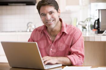Royalty Free Photo of a Man With a Laptop in the Kitchen