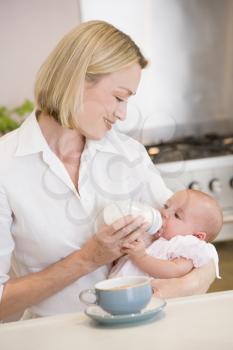 Royalty Free Photo of a Mother Feeding a Baby in the Kitchen