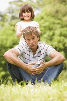 Royalty Free Photo of a Girl Putting a Daisy Chain on Her Dad's Head