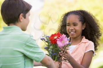 Royalty Free Photo of a Boy Giving a Girl Flowers