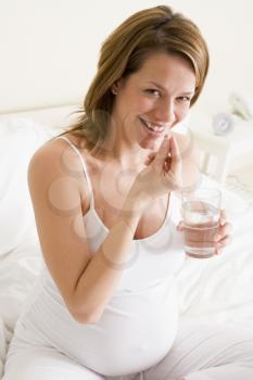 Royalty Free Photo of a Pregnant Woman With Medicine and Water