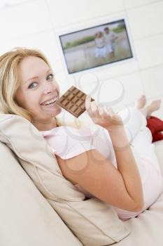 Royalty Free Photo of a Pregnant Woman Eating Chocolate in Front of the TV