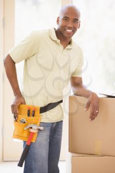 Royalty Free Photo of a Man Wearing a Tool Belt Leaning on Boxes