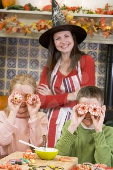 Royalty Free Photo of a Mother in a Witch Hat With Two Children and Halloween Treats