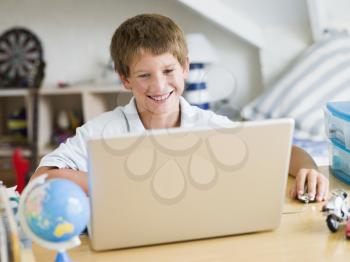 Royalty Free Photo of a Young Boy Using a Laptop in His Bedroom