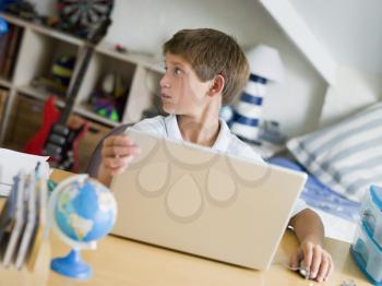 Royalty Free Photo of a Young Boy Using His Laptop in His Bedroom