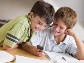 Royalty Free Photo of Boys Doing Homework and Holding a Cellphone