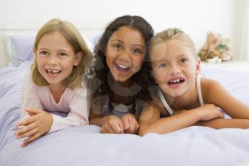 Royalty Free Photo of Three Girls Lying on a Bed in PJs