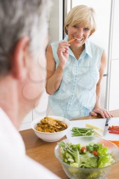 Royalty Free Photo of a Woman Preparing a Meal While Talking to Her Husband