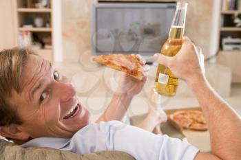 Royalty Free Photo of a Man Enjoying Beer and a Pizza in Front of the TV