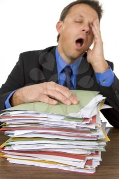 Royalty Free Photo of a Man Yawning Over Paperwork