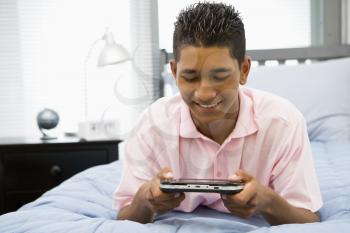 Royalty Free Photo of a Boy on His Bed Playing Video Games