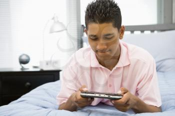 Royalty Free Photo of a Teenage Boy on His Bed Playing Video Games