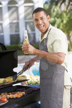Royalty Free Photo of a Man Barbecuing With Beer