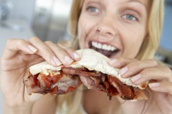 Royalty Free Photo of a Woman Eating a Bacon Sandwich