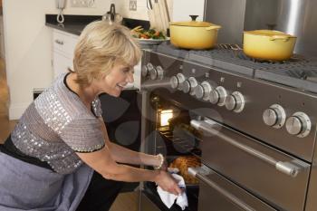 Royalty Free Photo of a Woman Taking Food Out of the Oven