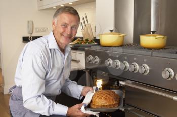 Royalty Free Photo of a Man Taking Food Out of the Oven