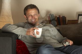 Royalty Free Photo of a Man Having Coffee and Watching TV