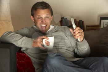 Royalty Free Photo of a Man With a Coffee Watching Television