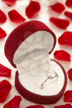 Royalty Free Photo of a Diamond Ring in a Heart Shaped Box Surrounded With Rose Petals