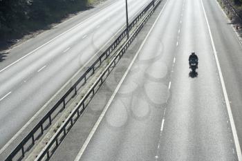 Royalty Free Photo of a Lone Biker on an Empty Highway